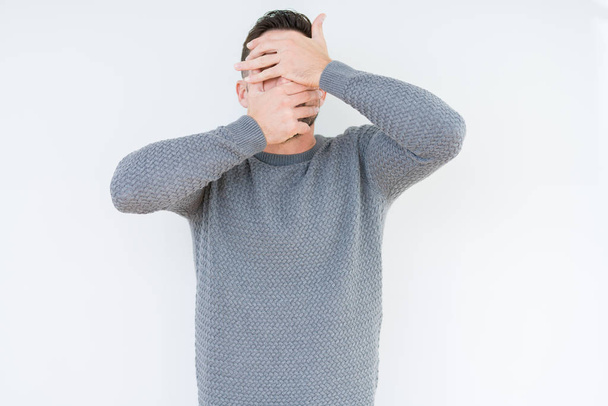 Mladý pohledný muž nosí ležérní svetr přes izolované pozadí krycí oči a ústa s rukama, překvapen a šokován. Skrývání emocí - Fotografie, Obrázek