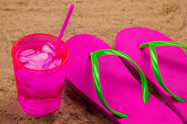 flip flops and cold drink with ice on a sand beach - Foto, imagen