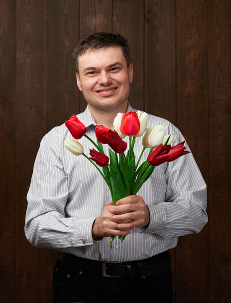 Man holds red flowers bouquet - Фото, изображение