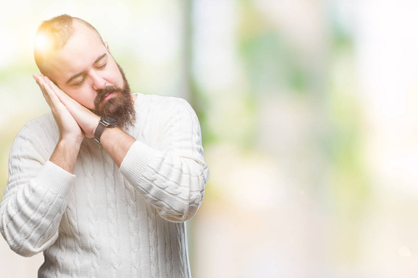 Hipster kaukaski młody człowiek sobie sweter zimowy na białym tle spania zmęczony marzy i pozowanie ręce razem podczas uśmiechający się z zamkniętymi oczami. - Zdjęcie, obraz