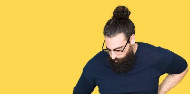Jonge hipster man met lange haren en baard dragen brillen lijden van rugpijn, aanraken terug met hand, spierpijn - Foto, afbeelding