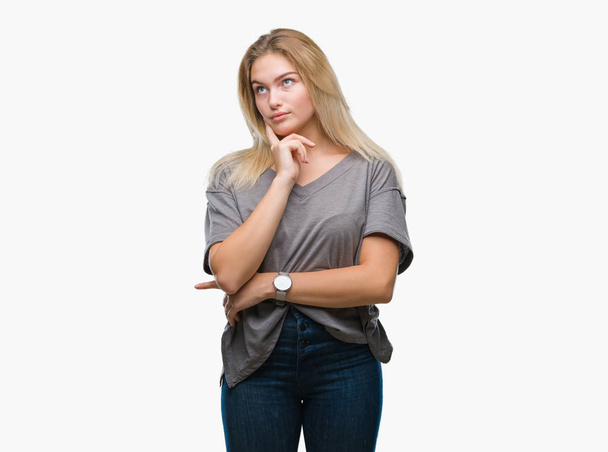 Young caucasian woman over isolated background with hand on chin thinking about question, pensive expression. Smiling with thoughtful face. Doubt concept. - Photo, image