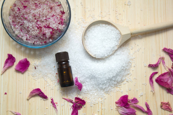 omemade scrub for body,sea salt in wooden spoon, aroma oil, rose petals on wooden background. Spa concept. - Foto, Bild