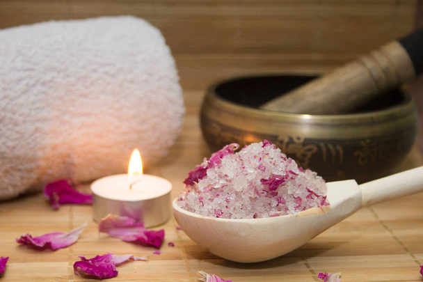 homemade body scrub from sea salt and rose petals and peony, Tibetan bowl,candle,pink towel on a straw Mat. Spa concept - Фото, изображение