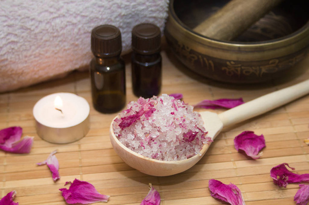homemade body scrub from sea salt and rose petals and peony, Tibetan bowl,candle,pink towel and aroma oil  on a straw Mat. Spa concept - Photo, image