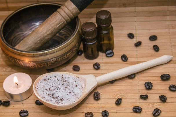 Spa concept.Coffee scrub, coffee beans, singing bowl, aroma oil, candle on straw mat  background - Foto, imagen