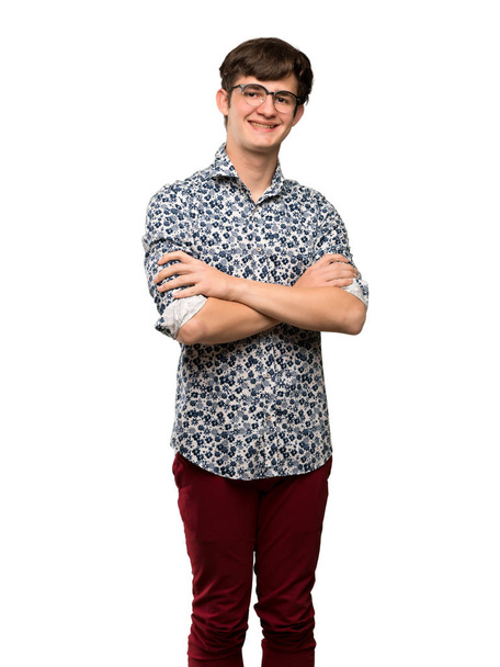 Adolescente uomo con camicia fiore e occhiali mantenendo le braccia incrociate in posizione frontale su sfondo bianco isolato
 - Foto, immagini