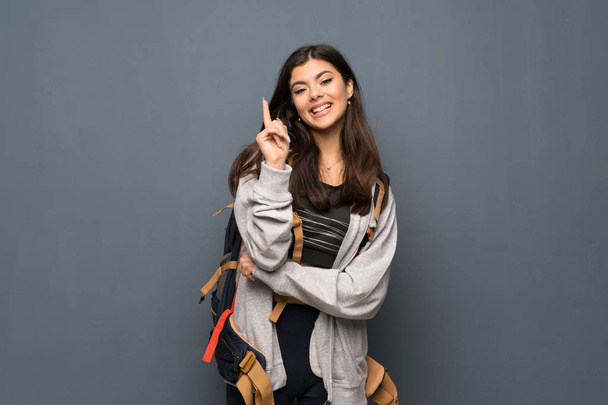 Teenager-Reisendes Mädchen über Mauer zeigt mit dem Zeigefinger eine großartige Idee - Foto, Bild