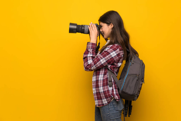 Photographer teenager girl over yellow wall  - Valokuva, kuva
