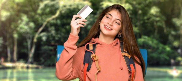 Turysta dziewczyna trzyma karty kredytowej i myślenia w na zewnątrz - Zdjęcie, obraz