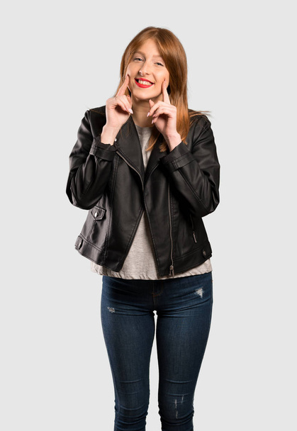 Jonge roodharige vrouw die lacht met een gelukkig en aangename uitdrukking over geïsoleerde grijze achtergrond - Foto, afbeelding