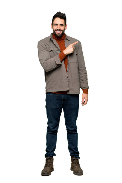 Full-length shot of Handsome man with beard pointing to the side to present a product on isolated white background - Photo, Image