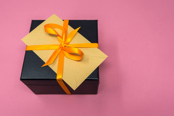 Caja de regalo de cubo negro con hueso de lujo, cinta naranja con sobre en la parte superior
 - Foto, Imagen