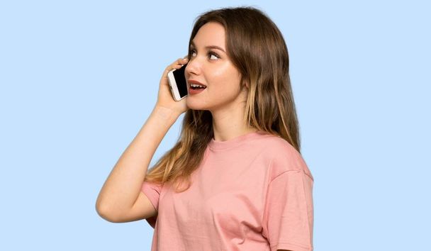 Nastolatek dziewczyna z różowy sweter prowadzenie rozmowy z telefonu komórkowego na na białym tle niebieski - Zdjęcie, obraz