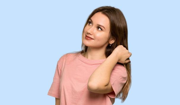Adolescente avec pull rose ayant des doutes et pensant sur fond bleu isolé
 - Photo, image