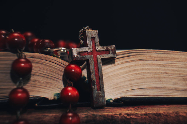 Old red Beads and crucifix on a Holy Bible background. Macro view. - Photo, Image
