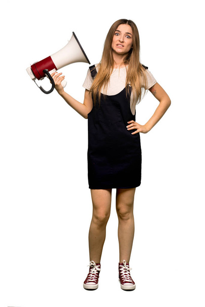 Full body Young pretty woman taking a megaphone that makes a lot of noise on isolated background - Foto, imagen