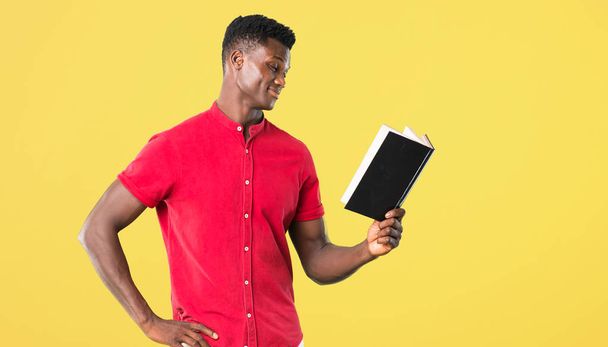 Молодой африканский американец держит книгу и наслаждается чтением о
 - Фото, изображение