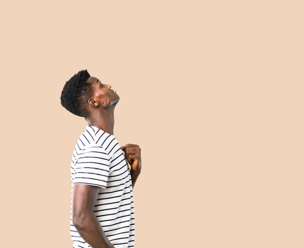 Dark skinned man with striped shirt stand and looking up on isol - Foto, Imagen
