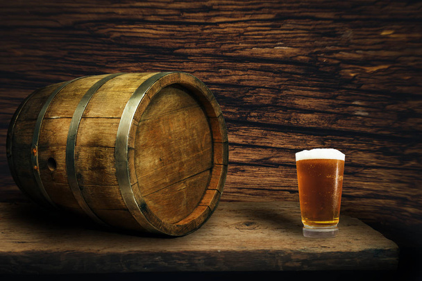 Дерев'яна бочка і келих пива на старому дубовому столі з дерева
. - Фото, зображення