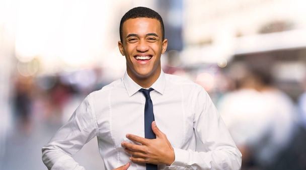 Jovem empresário afro-americano sorrindo muito ao colocar as mãos no peito na cidade
 - Foto, Imagem