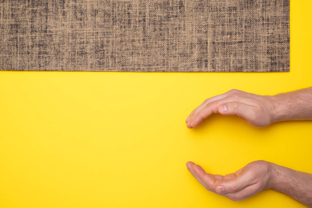 New yoga mat on a colored yellow background. Man hand show small size. - Fotoğraf, Görsel