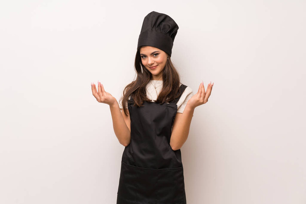 Teenager chef  over white wall making money gesture - Foto, afbeelding