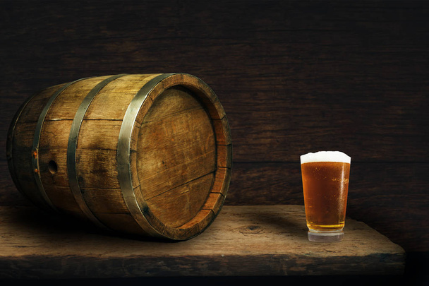 Houten vat en glas bier op een oud eiken tafel van hout. - Foto, afbeelding