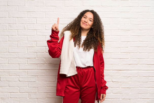 Teenager sport girl with curly hair showing and lifting a finger in sign of the best - Foto, imagen