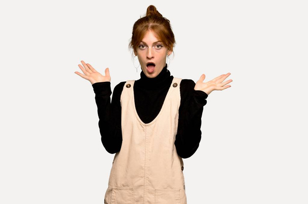 Young redhead woman with surprise and shocked facial expression over grey background - Foto, imagen