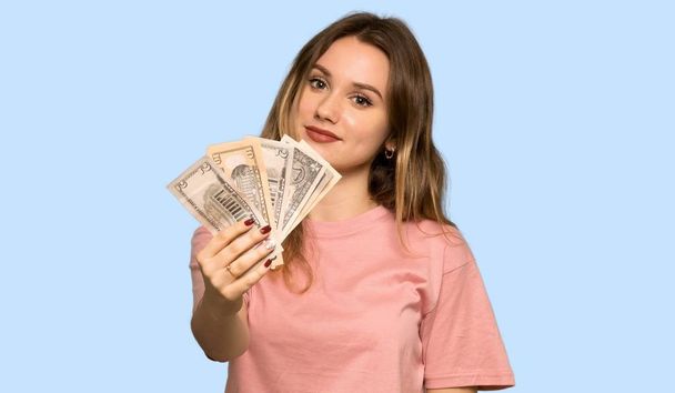 Дівчина-підліток з рожевим светром забирає багато грошей на ізольованому синьому фоні
 - Фото, зображення