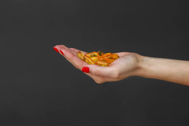 Scattering of transparent yellow pills. Handful of capsules in palm of hand, close-up, isolated on gray background. - Foto, afbeelding