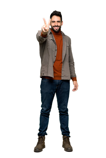Полнометражный снимок Красавчика с бородой, улыбающегося и показывающего знак победы на изолированном белом фоне
 - Фото, изображение