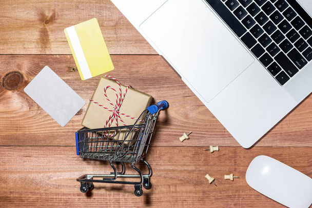 Shopping online concept. Small blue trolley and gadgets on the w - Fotoğraf, Görsel