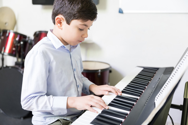 Selbstbewusster männlicher Schüler lernt in Musikschule E-Piano spielen - Foto, Bild