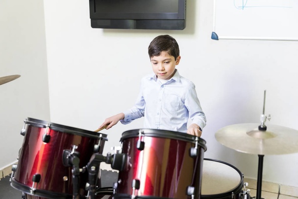 Little drummer practicing to play drums in music academy - Valokuva, kuva