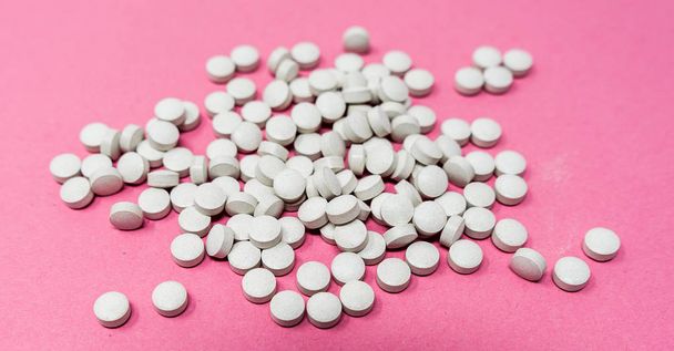 Много серых круглых таблеток на розовом фоне
 - Фото, изображение