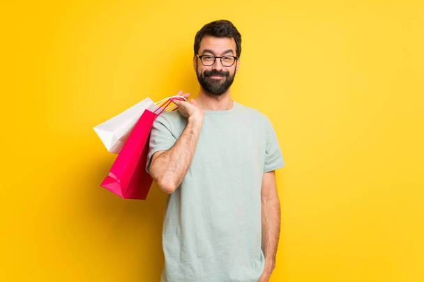 Ember a szakálla és zöld ing gazdaság egy csomó bevásárló táskák - Fotó, kép