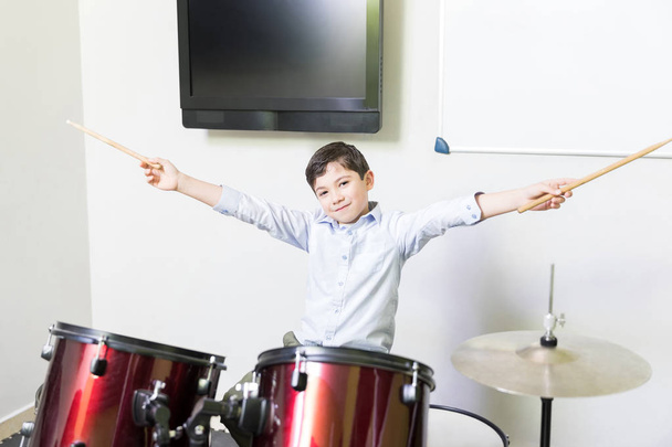 音楽学校でドラムをプレイを伸ばした腕を持つ少年の笑顔 - 写真・画像