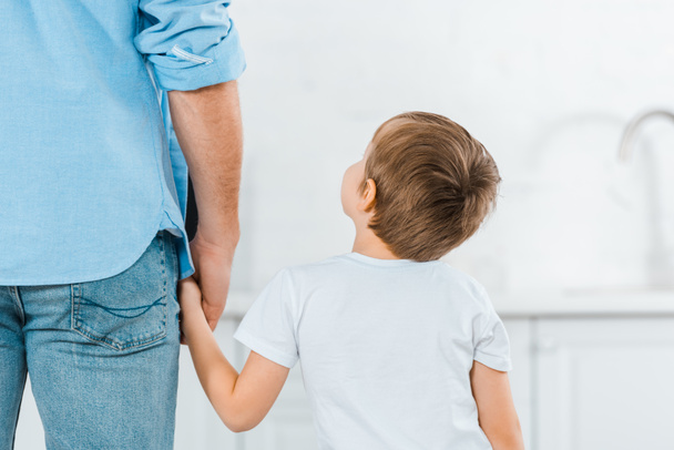 back view of preschooler holding hands with father at home - Foto, Bild
