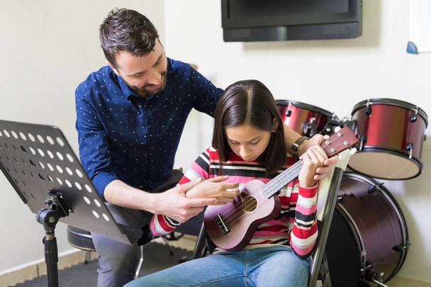 Hiszpanin mężczyzna nauczanie nauczyciel kobiet Nastolatki grać na ukulele w szkole muzycznej - Zdjęcie, obraz