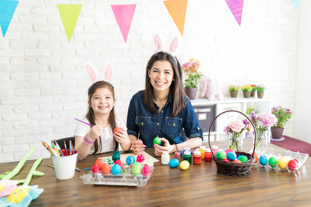 Retrato de madre creativa hija dúo con coloridos huevos de Pascua en la mesa
 - Foto, imagen