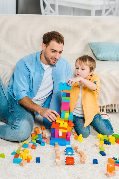 father and adorable preschooler son playing with colorful building blocks at home - 写真・画像