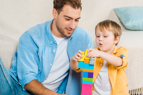apa és imádnivaló óvodás fia játszik a színes építőkockák otthon - Fotó, kép