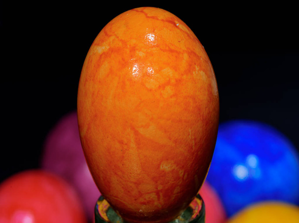macro de arte de un aislado transformado solo amarillo naranja brillante detallada textura huevo de Pascua sobre fondo borroso de colores y negro
  - Foto, imagen