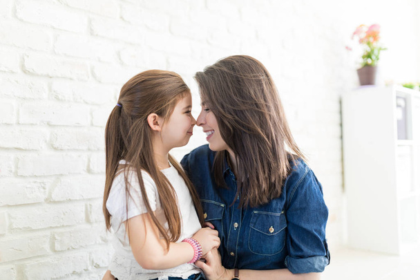 Любящие мать и дочь массируют носы, проводя время вместе дома
 - Фото, изображение