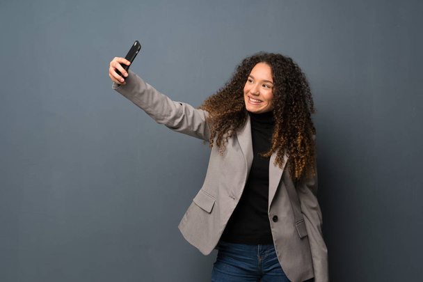 Tiener meisje over blauwe muur maken een selfie - Foto, afbeelding