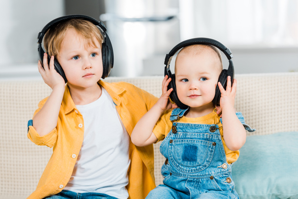 adorable brothers listening music in headphones at home - Photo, Image