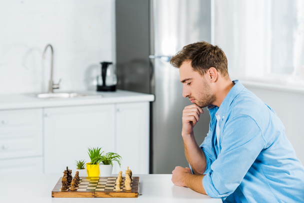 töprengő ember ül az asztal, rövid idő játék sakk otthon - Fotó, kép