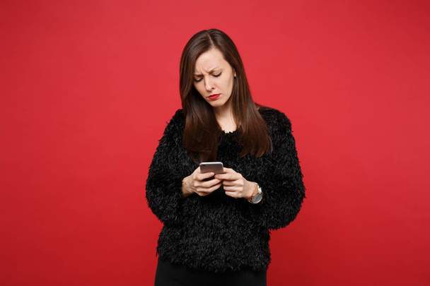 Perturbado mulher jovem perplexo em camisola de pele preta usando phon móvel
 - Foto, Imagem